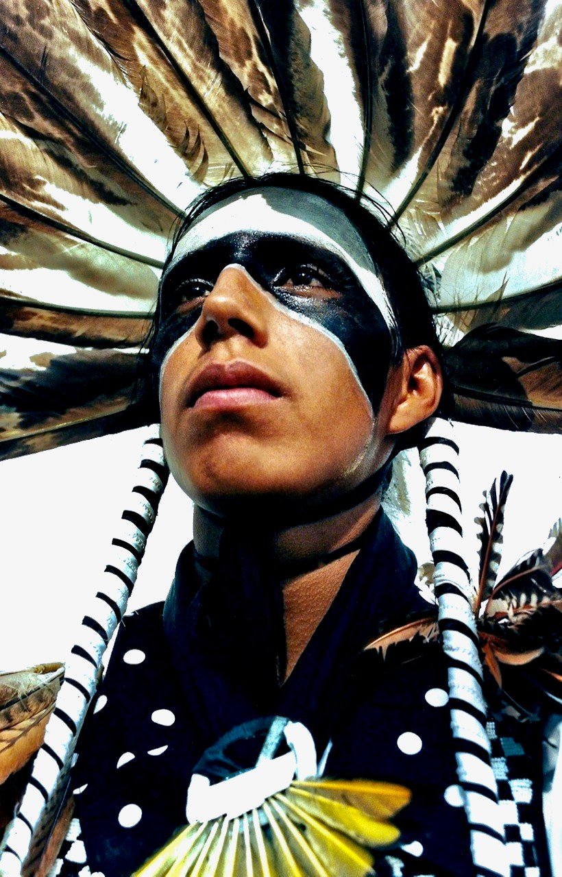 A Native American with facial makeup and traditional clothing.