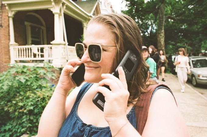 The author using an iPhone and a dumb phone