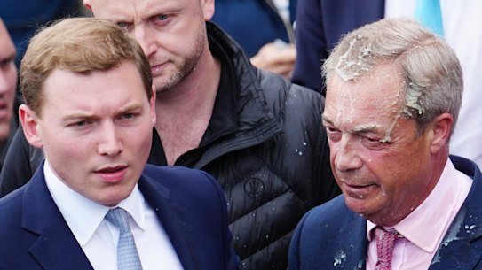 George Cottrell, wearing a blue tie, was with Farage when a woman threw a milkshake at him while campaigning in 2024.