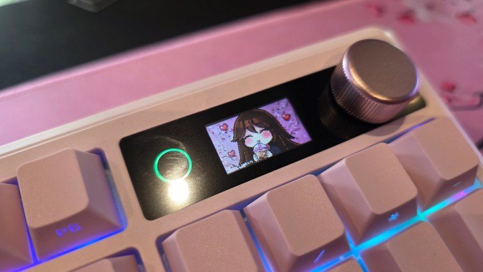 Close-up of the keyboard's LCD screen showing the light next to it, the glowing knob, and a custom gif of my character drinking boba.