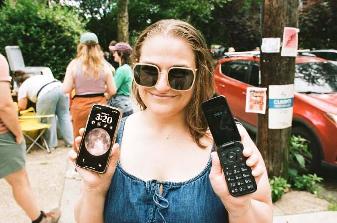 The author using an iPhone and a dumb phone