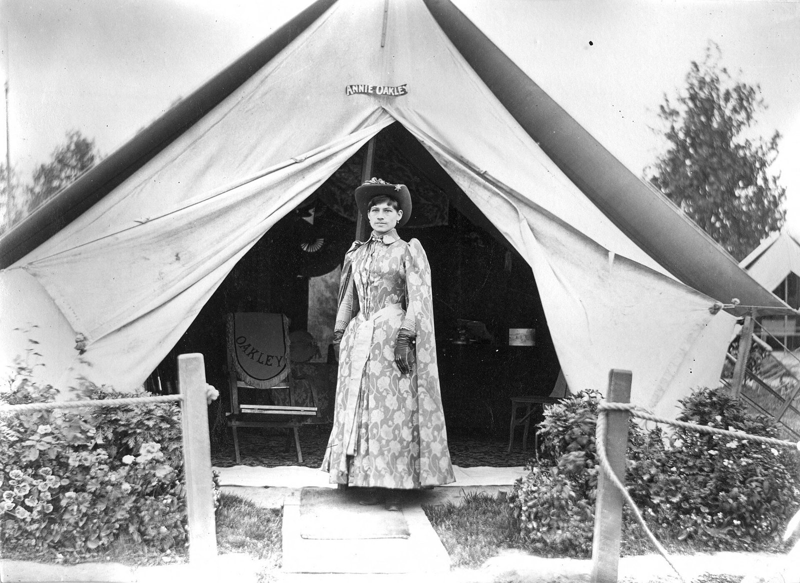 Young woman dressed in cape poses in front of a tent.