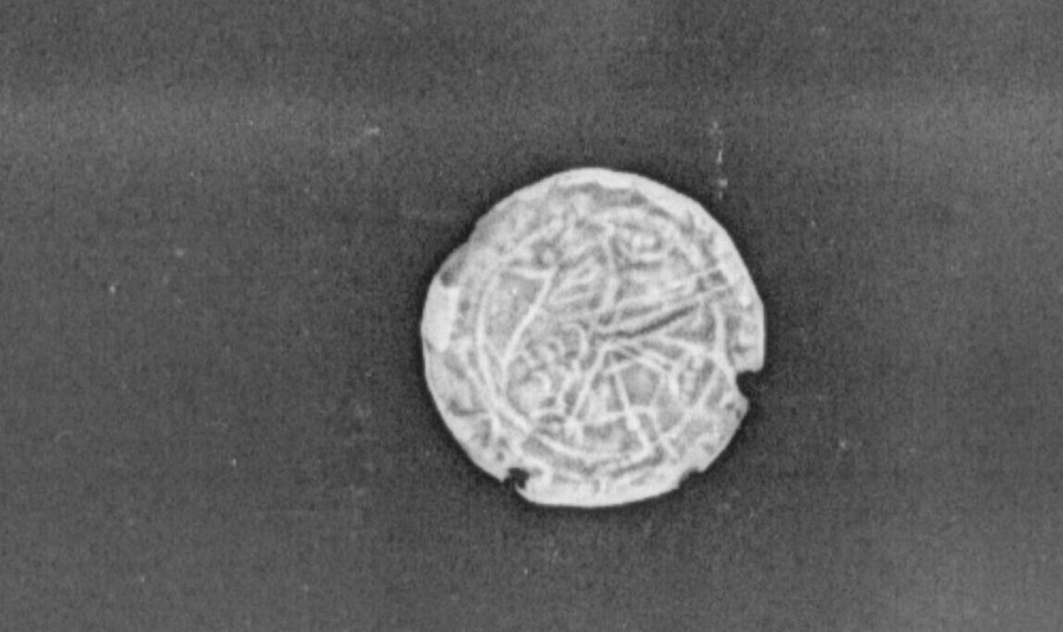 X-ray image of the face of a Viking coin showing the outline of the griffin design.