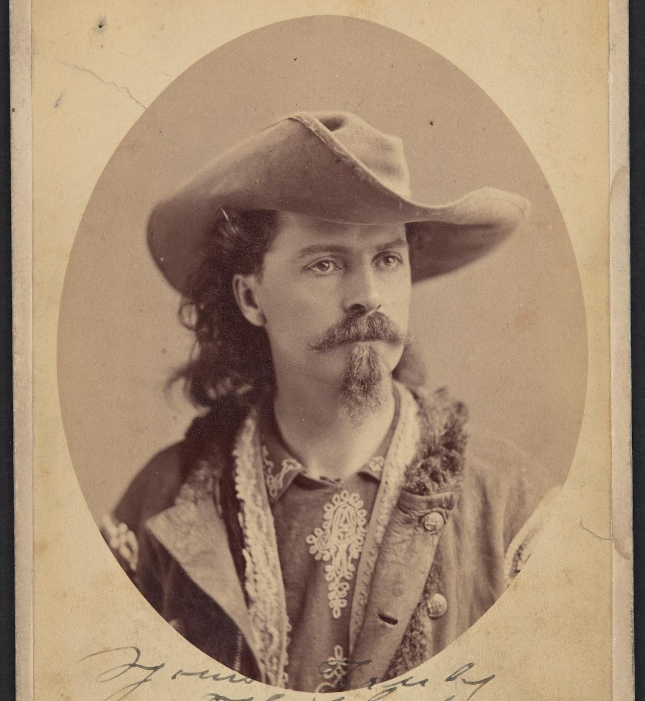 Old photograph of a young man with a cowboy hat, mustache and goatee. 