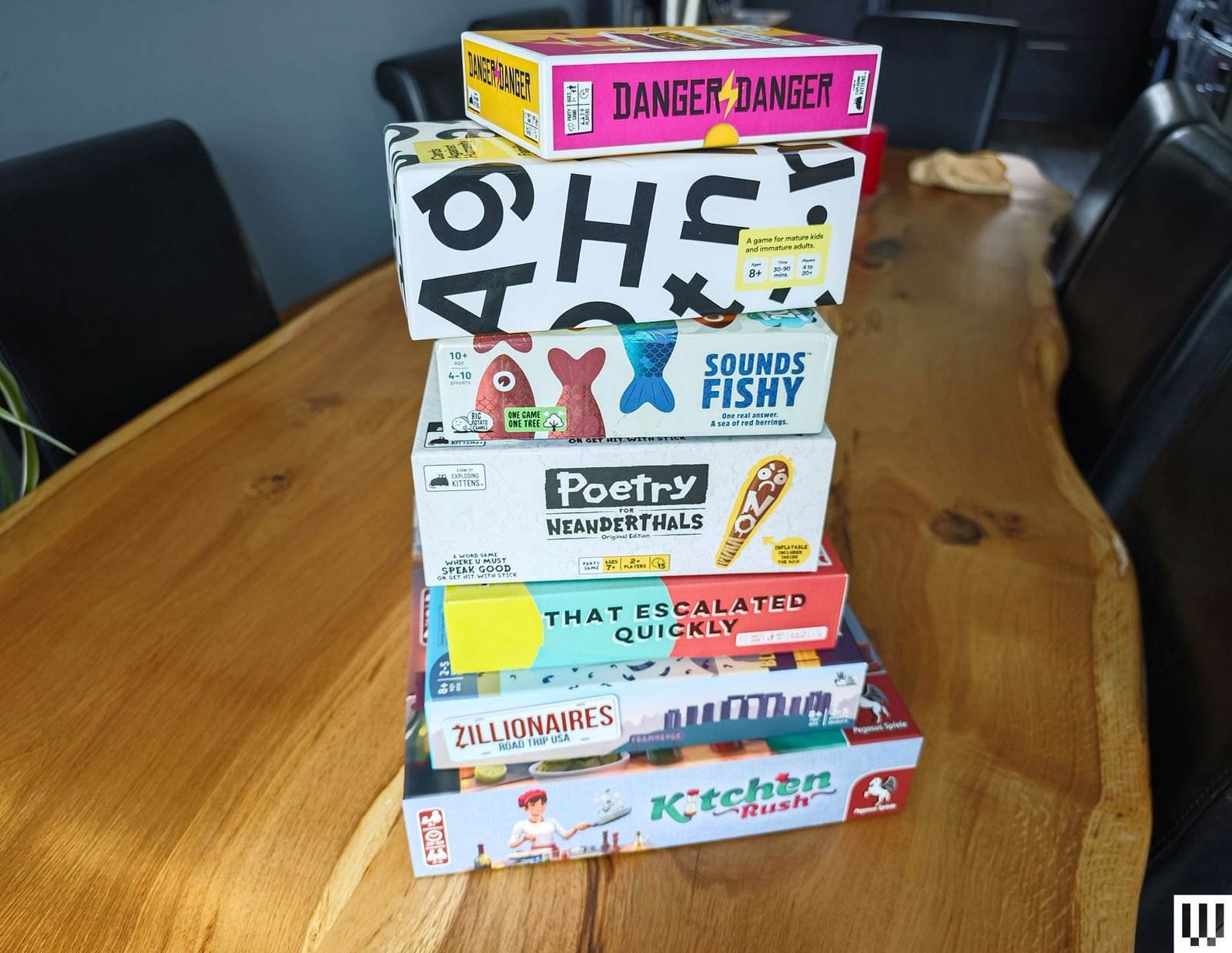 Stack of board game boxes on a large wooden table