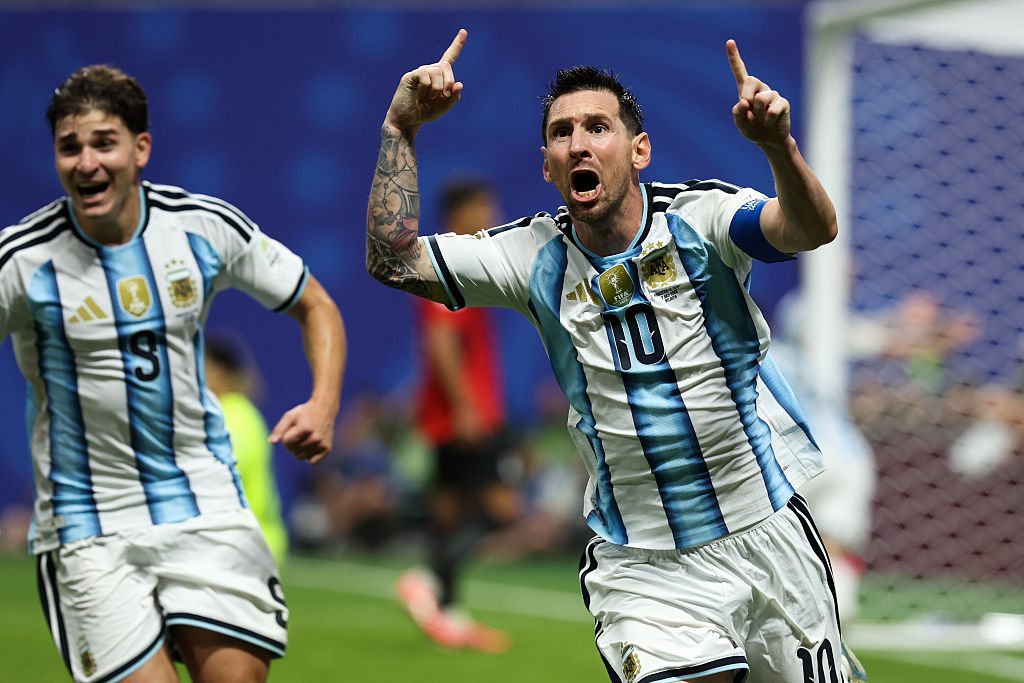 Lionel Messi celebrates the goal with his fingers pointing in the air.