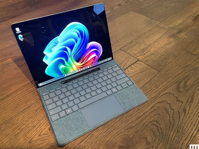 Microsoft Surface Pro tablet connected to a detachable keyboard, sitting on a wooden floor.