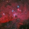 NASA’s Hubble captures a crimson cloud glowing with white and blue stars