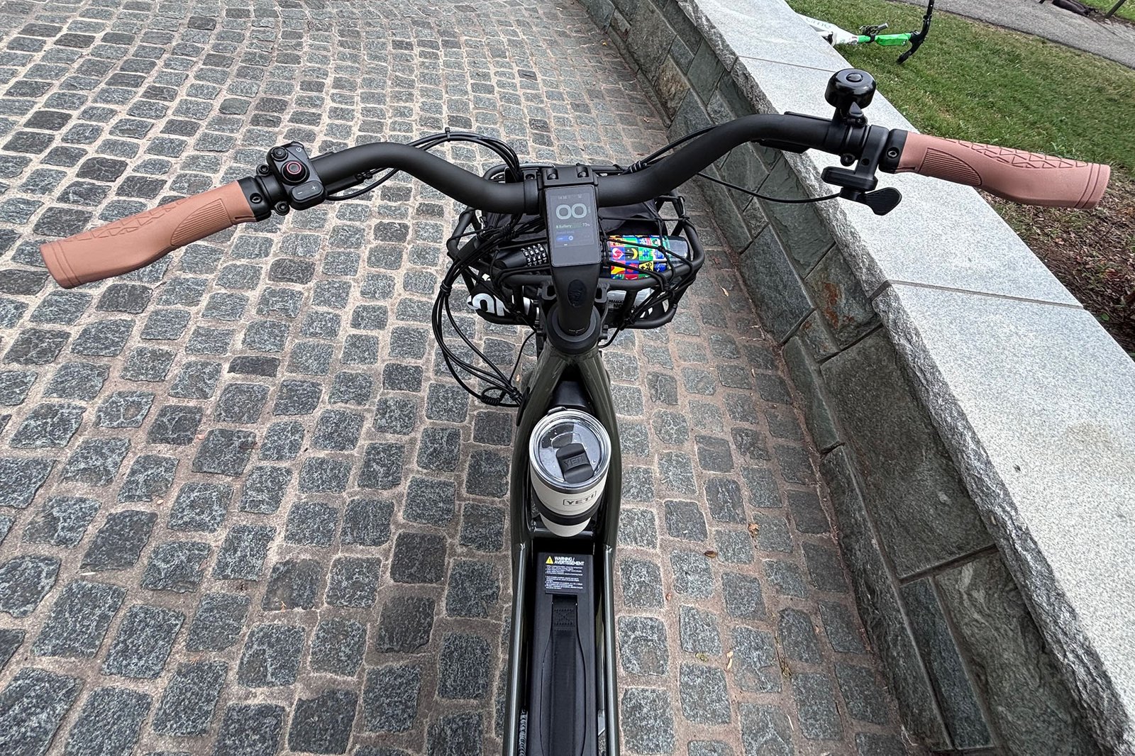Handlebars of the Segway MUXI electric cargo bike sitting on cobblestones next to the bike path at the entrance to Theodore Roosevelt Island.