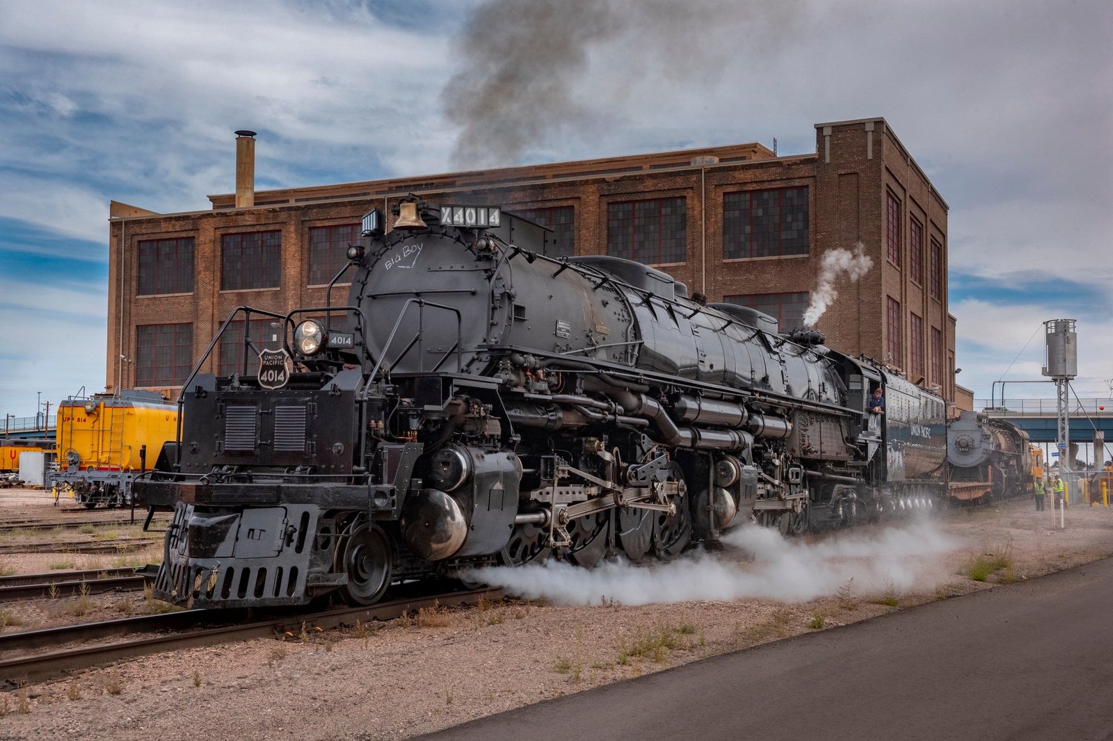 A large steam train outside a building.
