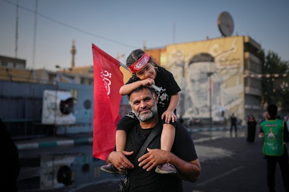 A man carries a child holding a Shiite religious flag in front of Imam Khomeini Mosalla in Tehran.