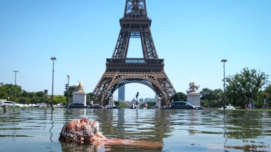 A man cools off in the Warsaw Fountain in the Trocadéro Gardens, in front of the Eiffel Tower in Paris.