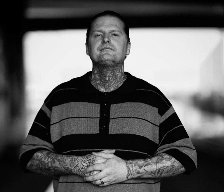 Black and white photograph of Ryan Rising standing with his hands clasped in front of him.
