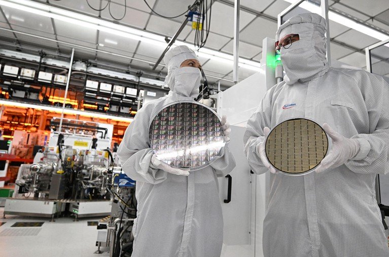 Two employees at PPE manipulate gallium nitride (GaN) wafers of different sizes inside a fully automated clean room at a semiconductor facility.