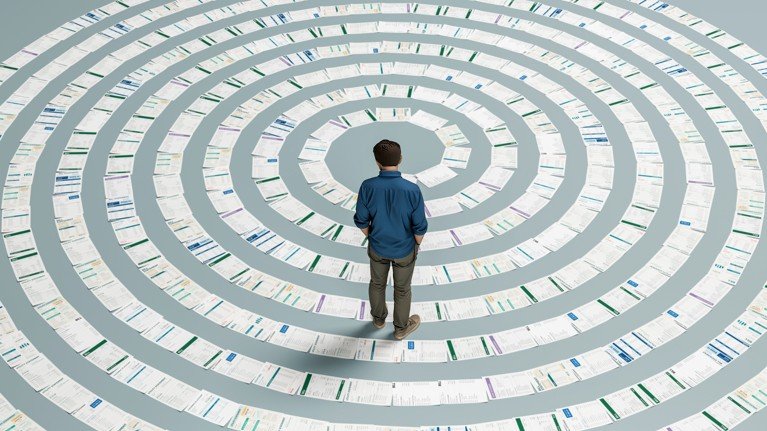 A man standing looking down on a line of different papers arranged in a spiral shape.