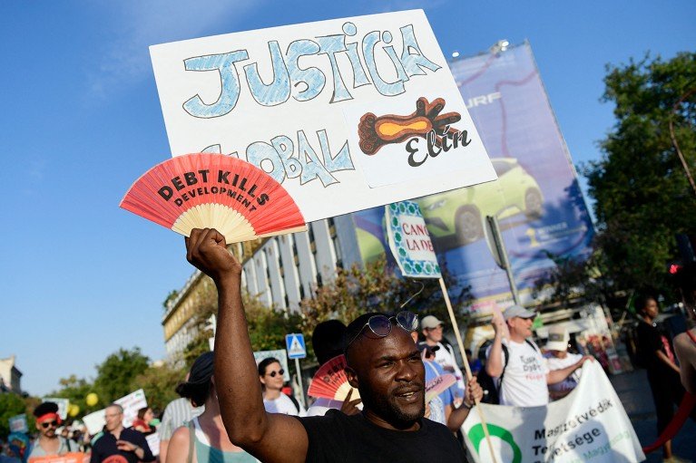 A man holds a sign that says "global justice" During a protest march in Spain to demand UN-led solutions to the sovereign debt crisis and global wealth inequality.