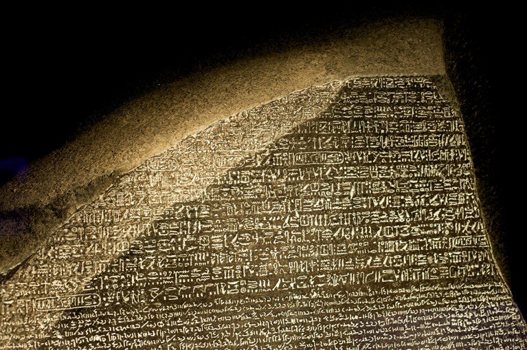 A replica of the Rosetta Stone showing the top of the stone with ancient hieroglyphs followed by demotic writing.