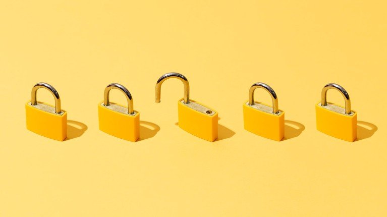 Five padlocks placed in a row. One of them is open.