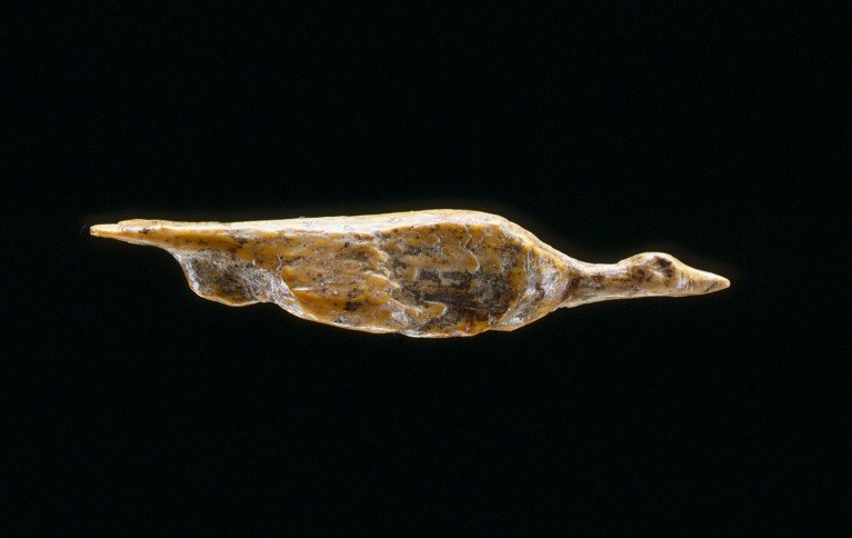 A small bird-shaped figure photographed on a black background.