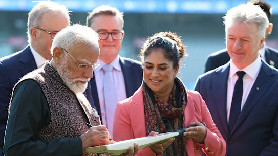 Indian Prime Minister Narendra Modi signs a bat for former Australian cricketer Lisa Sthalekhar, alongside Steve Waugh. 