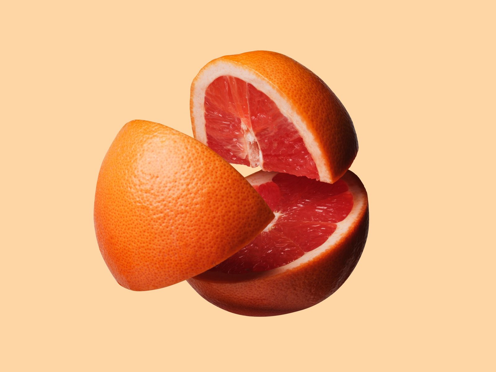 Grapefruit cut into three pieces, floating in the air.