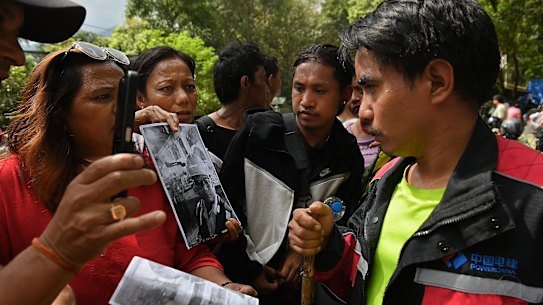 Tunnel survivor Dhan Bahadur Tamang (right) speaking women desperate to know the whereabouts of a missing loved one. 
