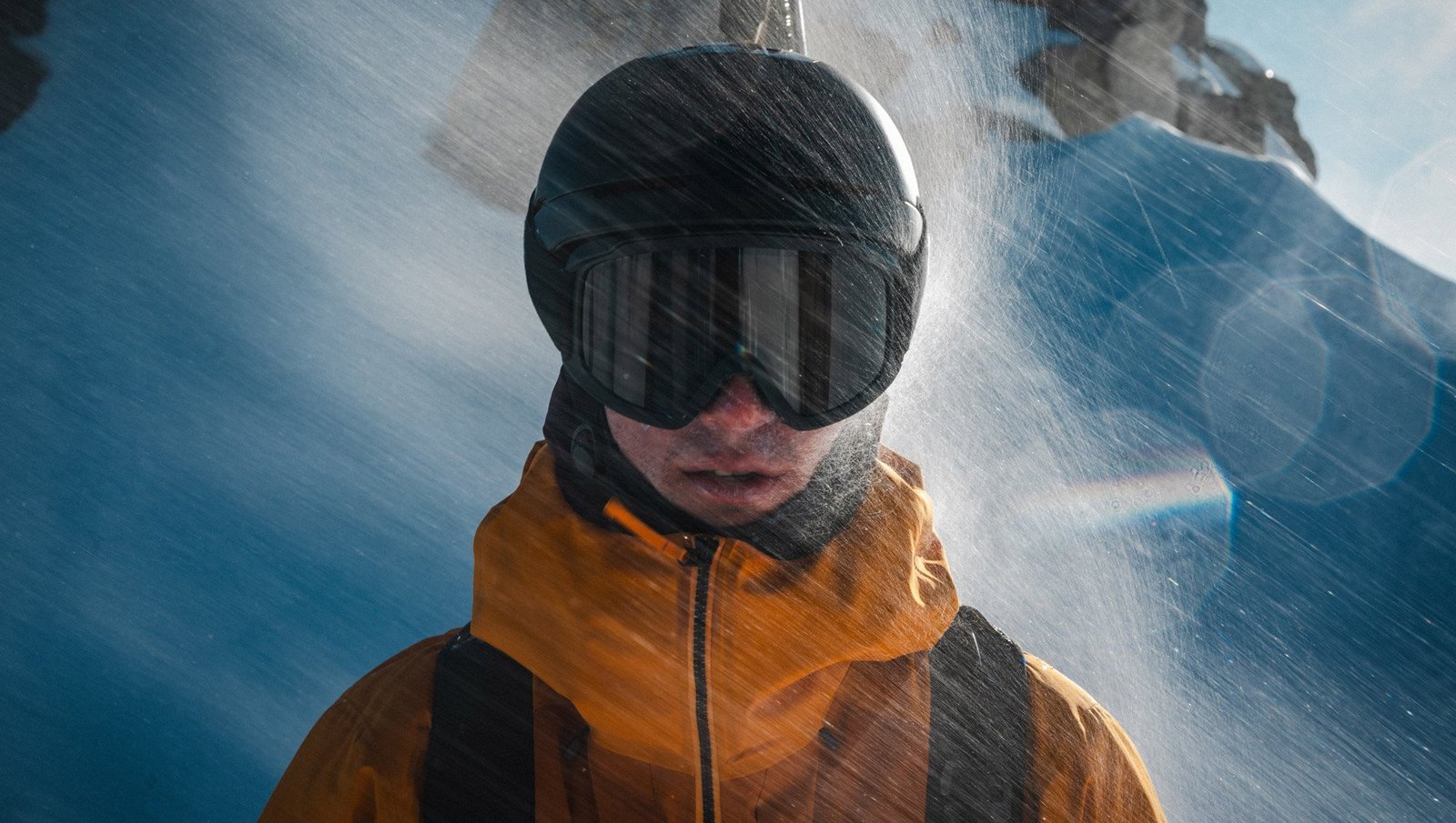 A person wearing a helmet and goggles getting hammered with snow wearing the Arc'teryx Sperro SV jacket