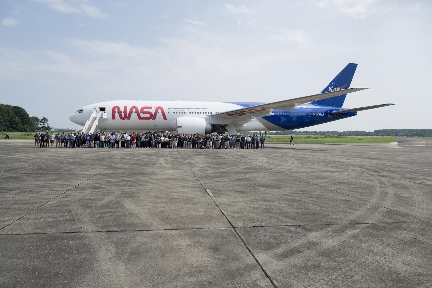 NASA B77 plane on runway with attendants and crew standing in front of it