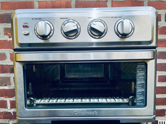 Cuisinart TOA-70 Air Fryer Oven and Grill sitting on a white table in front of a brick wall