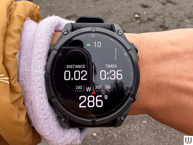 A wrist wearing a black Garmin Fenix 8 AMOLED, a digital wristwatch for fitness tracking with the watchface screen showing distance and timer
