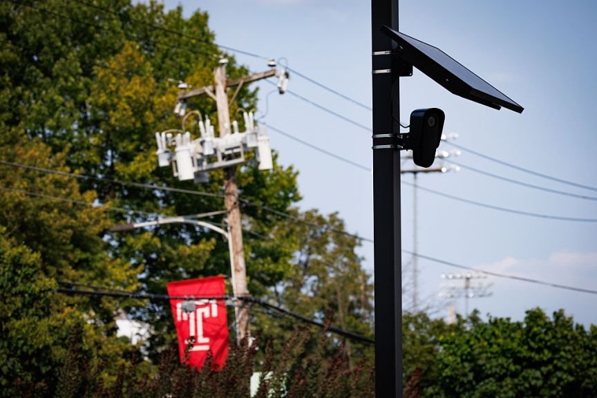 A Flock camera and solar panel next to power lines.