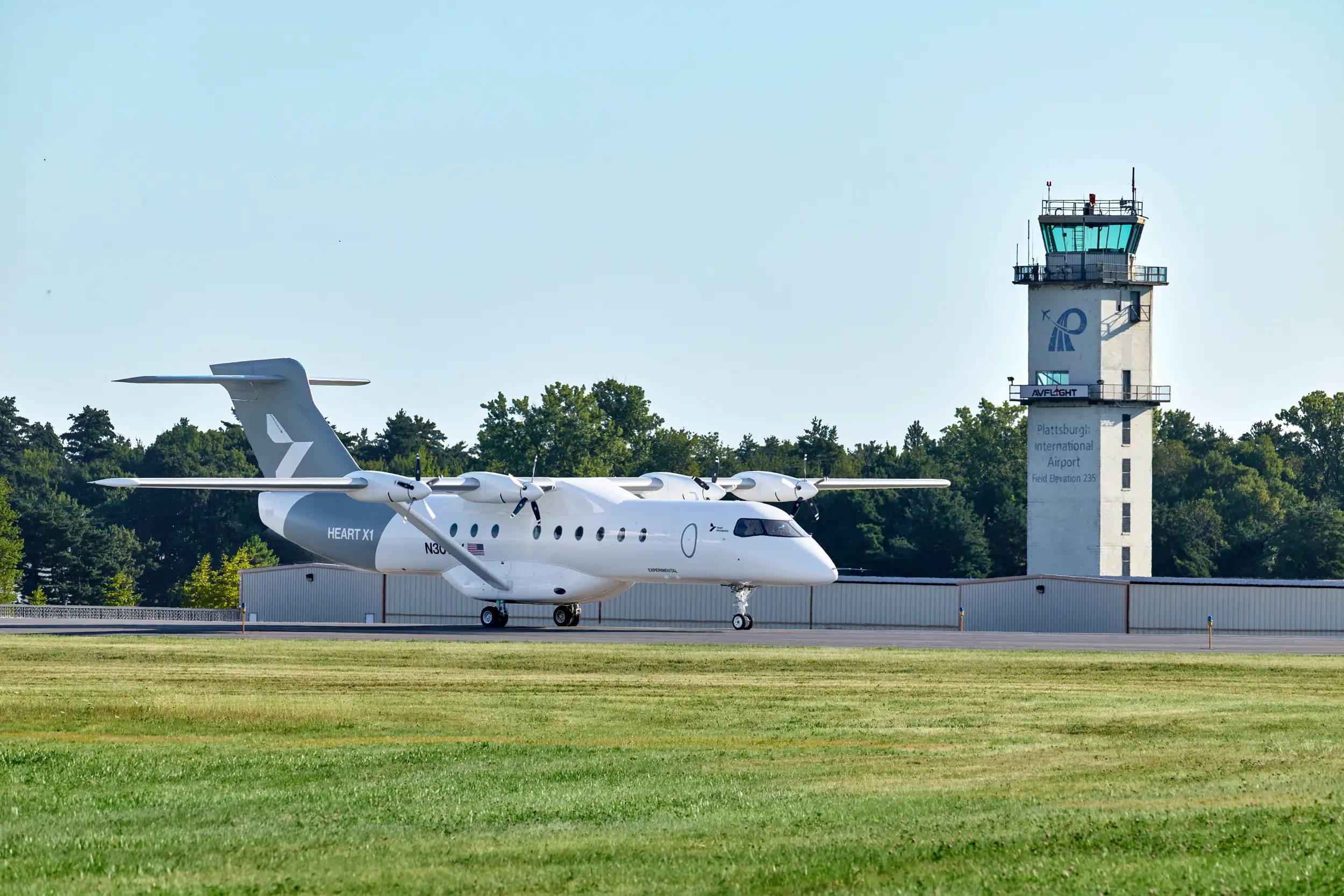 a small white plane on a runway next to an air traffic control tower
