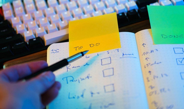 Close-up view of someone writing a to-do list in a notebook with a pen.