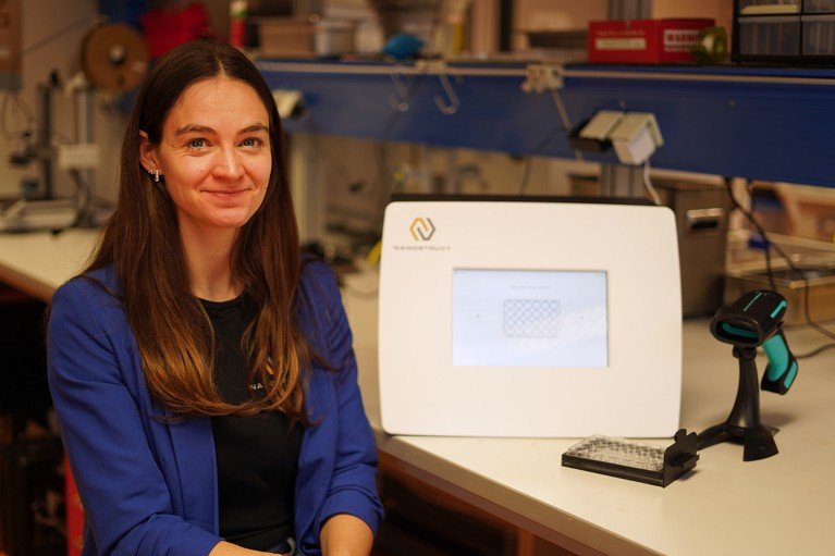 Henriette Maaß seated in a laboratory with a NanoStruct bacteria-testing machine by her side.