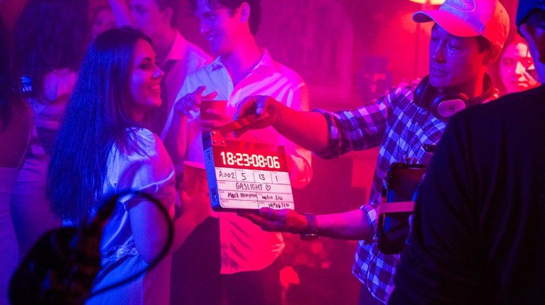 Woman smiles while a clapperboard is held up during the filming of Gaslight.