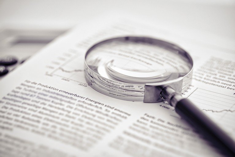 Close-up view of a magnifying glass resting on a page from an academic study.