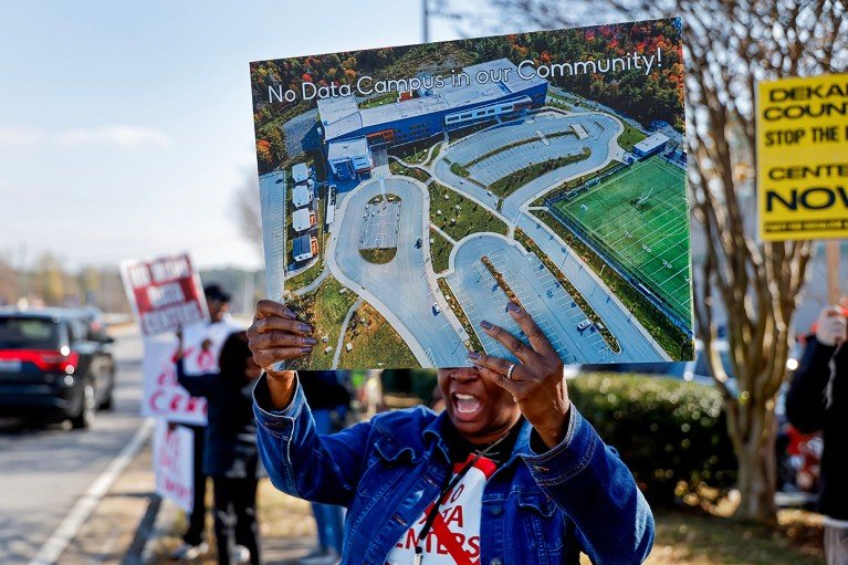 Demonstrators hold signs up while participating in a protest against a planned data centre in their area.
