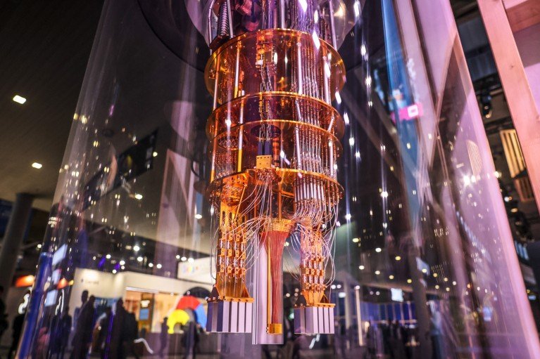 A close-up view of a quantum computing processor suspended inside a transparent cylindrical enclosure
