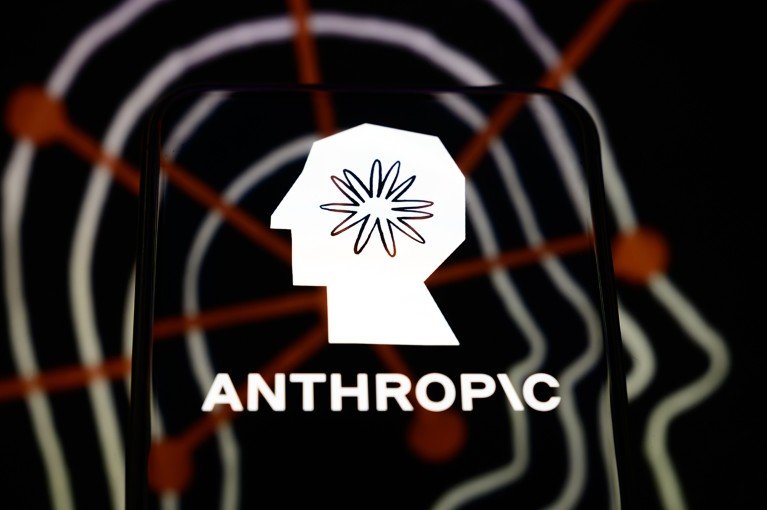 The Anthropic logo is displayed on a smartphone screen, placed on a reflective surface onto which a company branding illustration is projected.