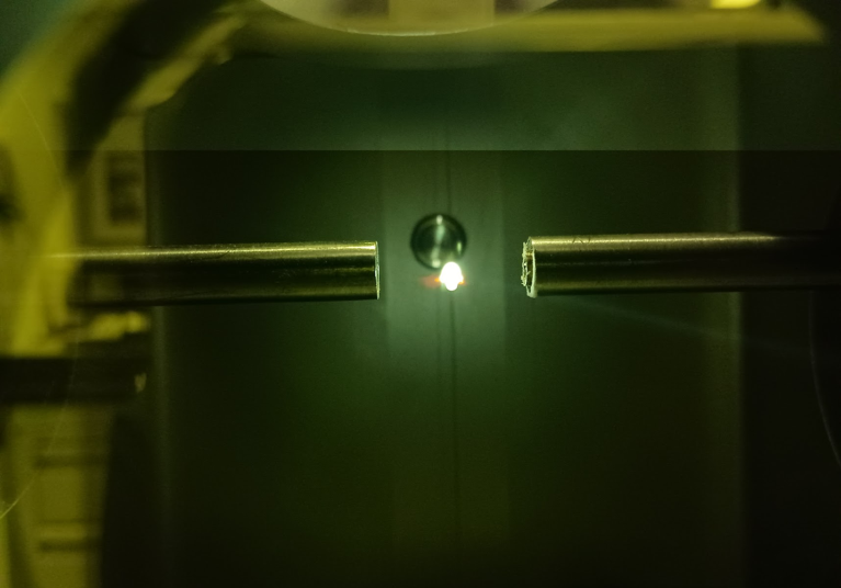 A bright light is seen between two cylindrical objects, covered by a green hue.