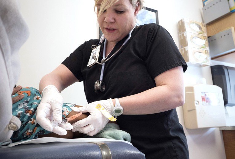 A nurse administers an MMR vaccination to a child receiving care at a clinic in Minneapolis.