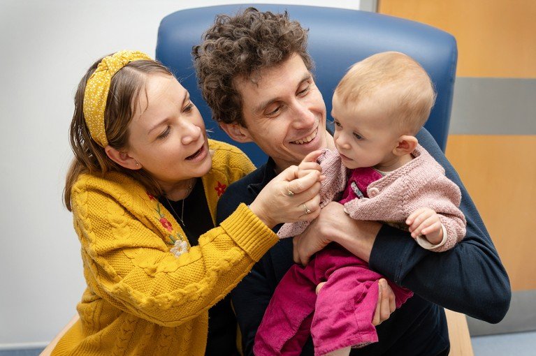 Baby Safi, mum Dorka and dad Cameron cuddle together on a chair.