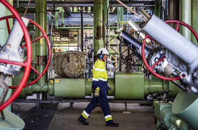An employee walks past pipes and industrial equipment at Neste’s Maasvlakte refinery, where biodiesel and sustainable aviation fuel are produced.