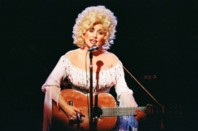 Dolly Parton performs with an acoustic guitar on stage in London in 1983.