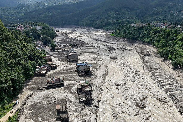 Aerial view of houses lying partially submerged in muddy water along a riverside, after the flash floods in Nepal.