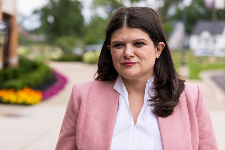 Woman in pink blazer stands