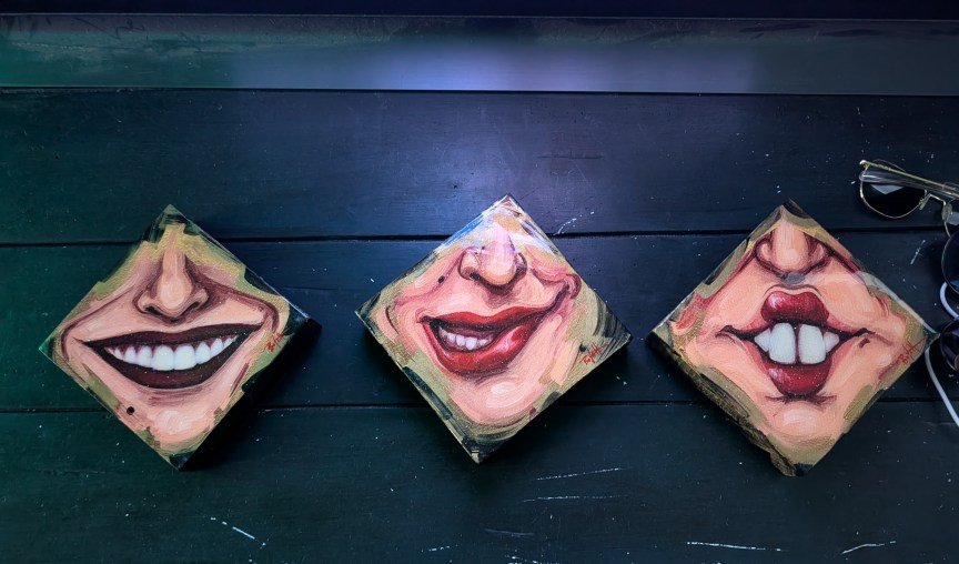 An artist's piece showing three diamonds with noses and smiling mouths in them