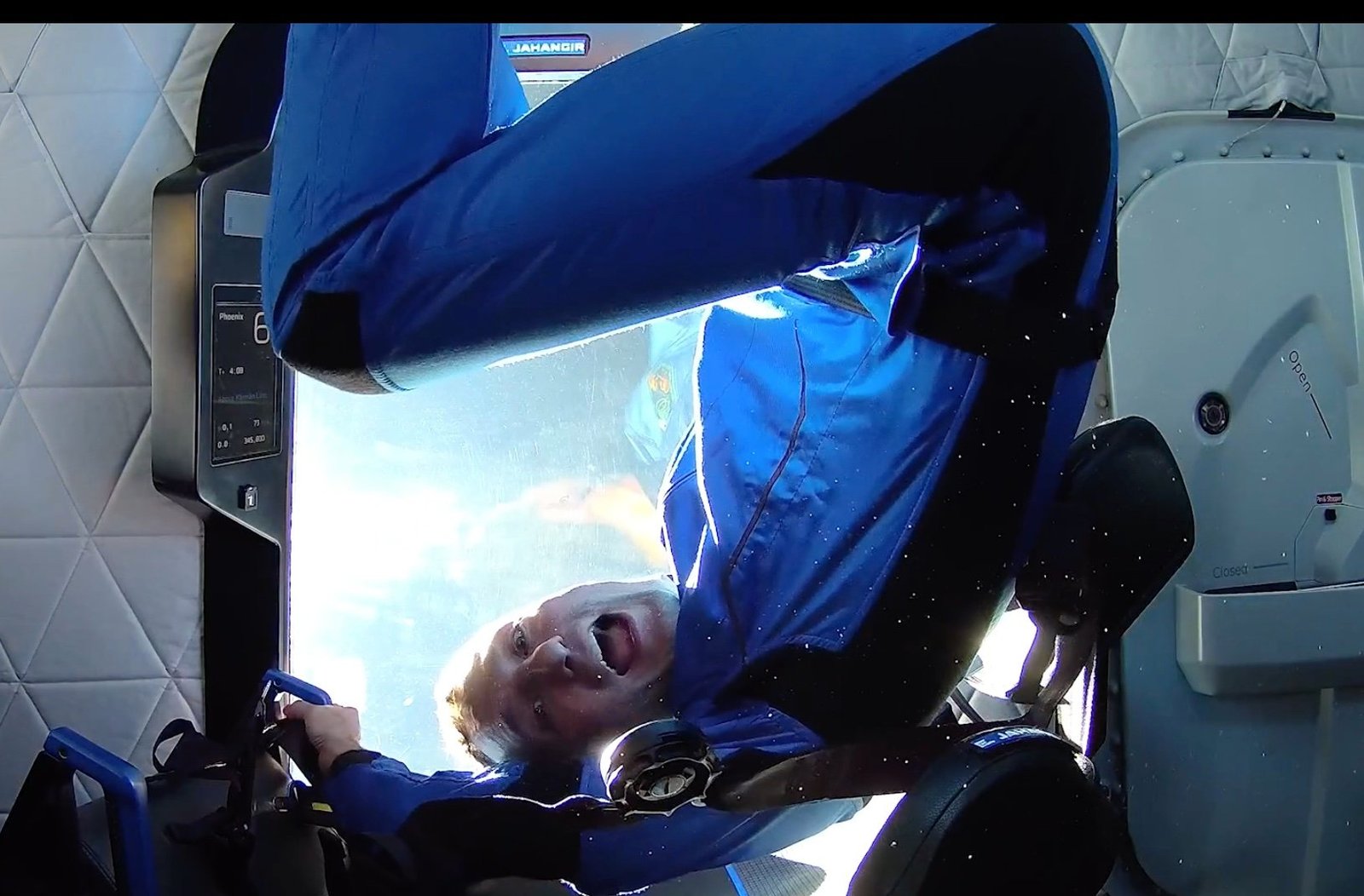 a man in a blue flight suit in zero gravity