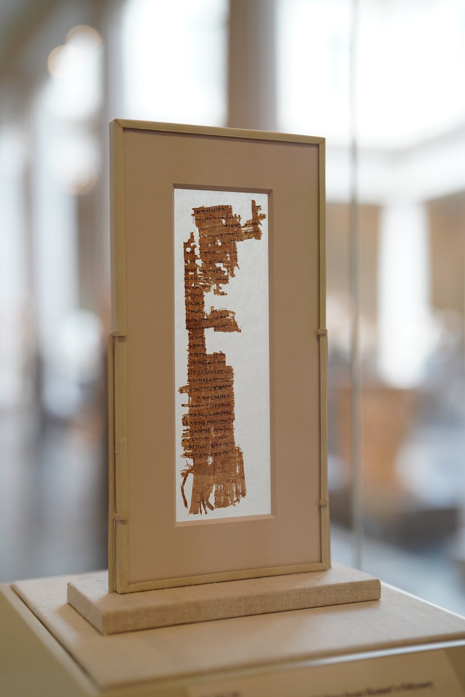 a piece of parchment on display in a museum behind glass. the parchment is from homer's "odyssey."