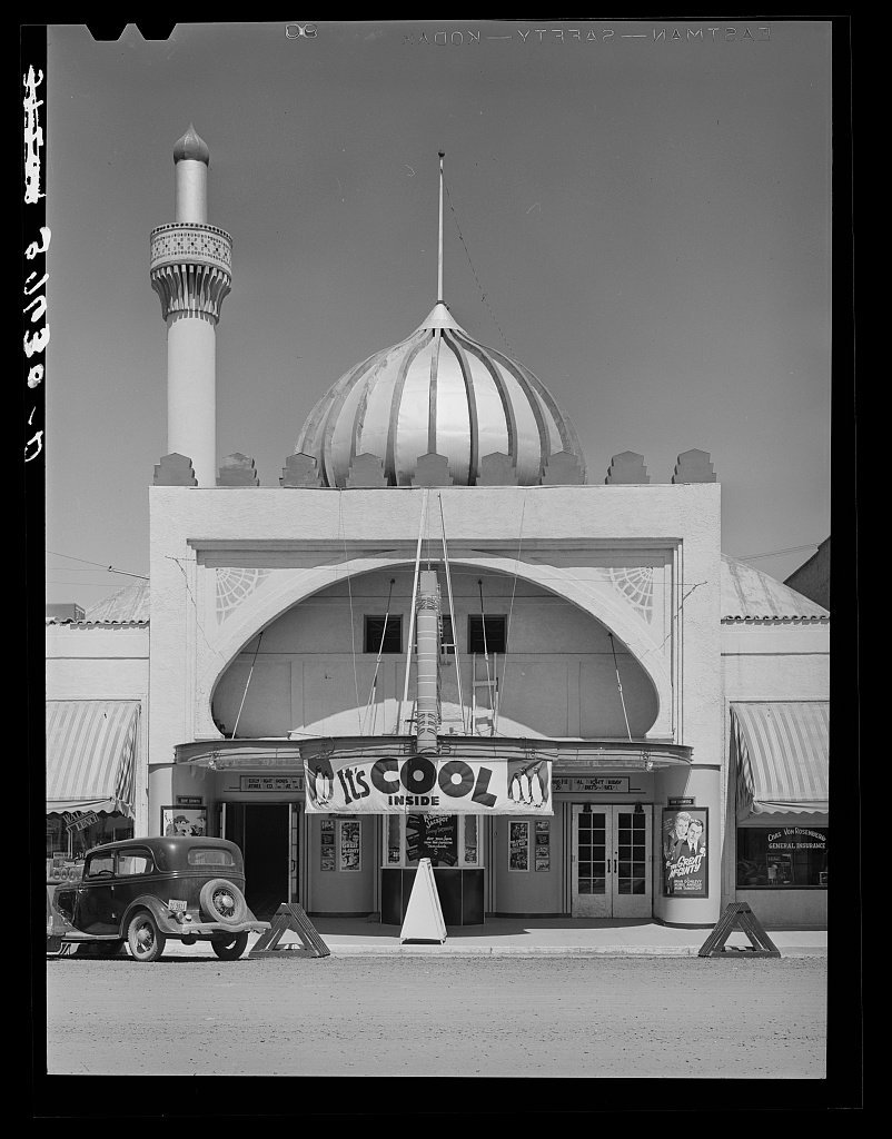 Vintage black and white theater has sign reading "It's cool inside"